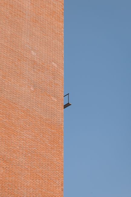Low angle view of a sunlit brick building contrasting with a clear blue sky.