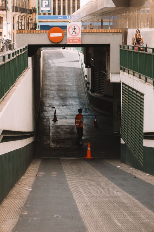 Free A city underground entrance with a security guard in orange vest and traffic cones. Stock Photo