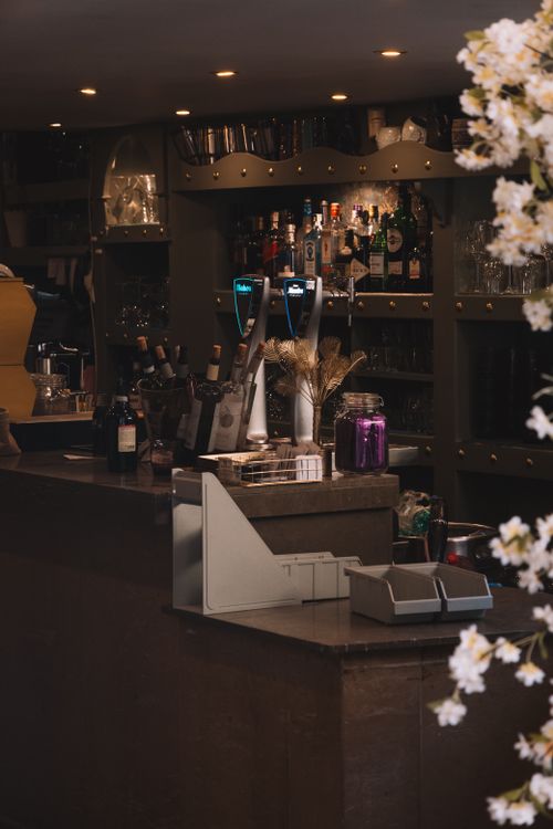 Free Elegant bar interior featuring floral decor and stylish drink displays, ideal for a cozy ambiance. Stock Photo