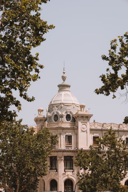 A vertical shot of Valencia's iconic Edificio de Correos framed by lush greenery.