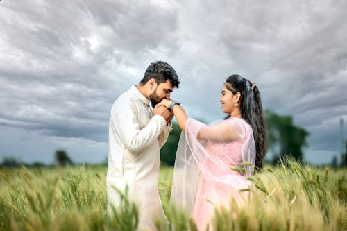 Man Kissing Hand of Smiling Woman in Field