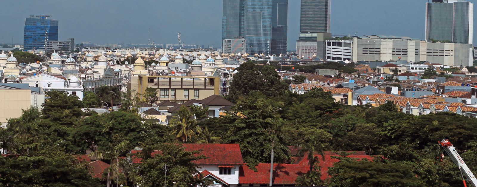 A vibrant cityscape featuring towering skyscrapers and lush greenery under a blue sky.