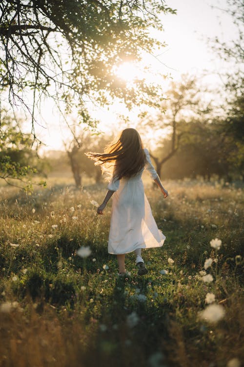 Young Woman Running Across the Meadow Towards the Sun
