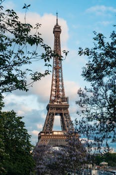 The iconic Eiffel Tower in Paris, surrounded by blooming trees and a vibrant sky.