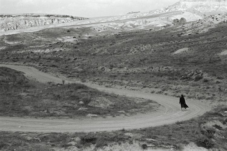 Woman Walking On Dirt Road In Black And White