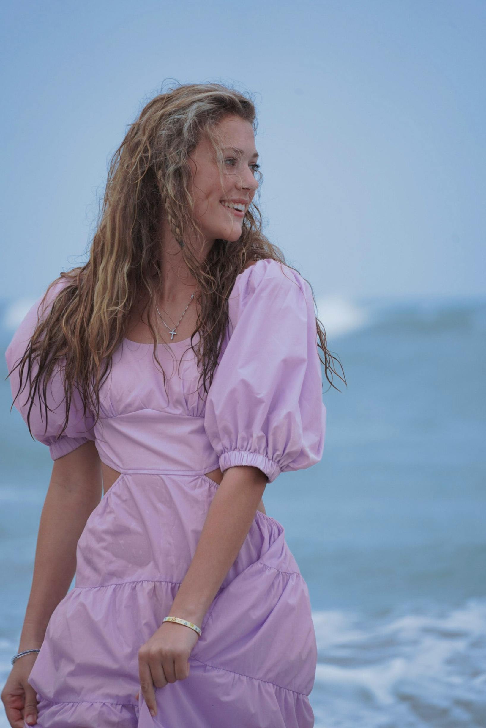 Smiling woman in a lavender dress enjoying the beach at Melbourne, FL.