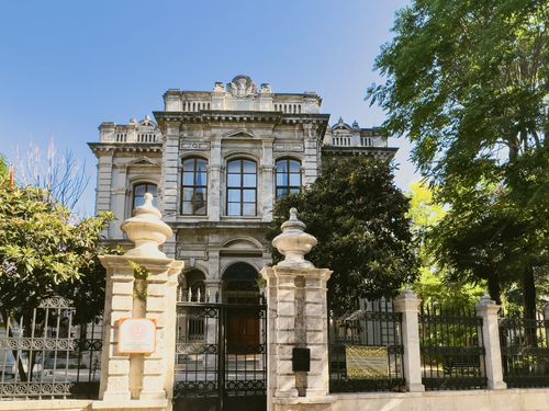 Free Elegant historical building with ornate architecture in Istanbul, Turkey framed by trees and iron gates. Stock Photo
