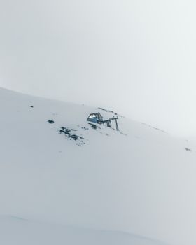 A solitary cabin on a snowy mountain slope, offering a sense of isolation and tranquility.
