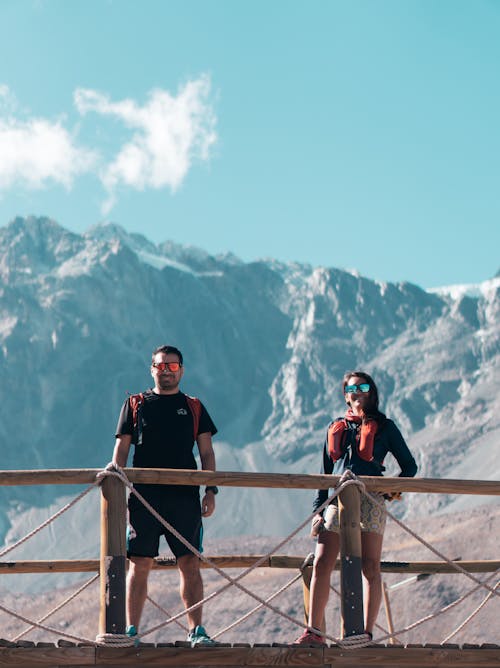 Man and Woman Standing on a Bridge in Mountains and Smiling