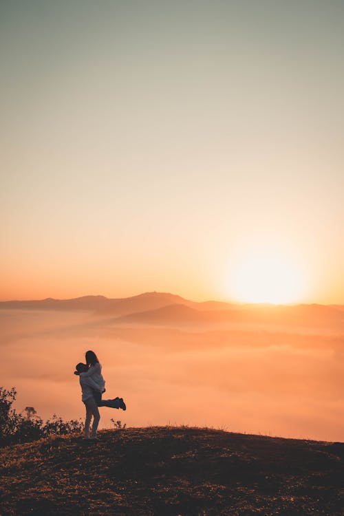 Couple Embracing on Hill at Sunset
