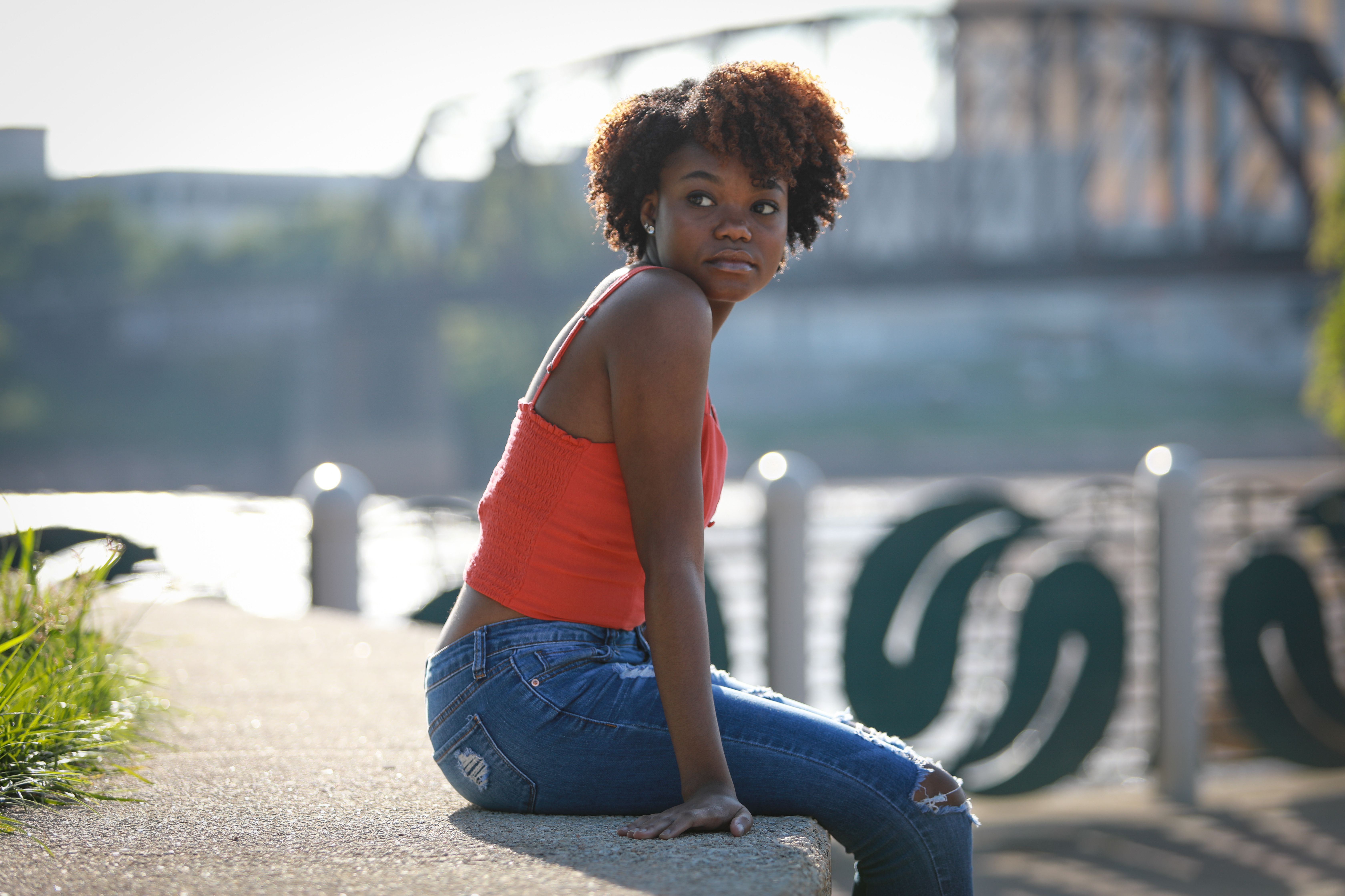Woman in Red Top and Jeans Sitting on Concrete · Free Stock Photo