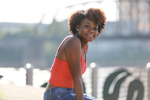 Young Woman Sitting Outside in City in Summer and Smiling 