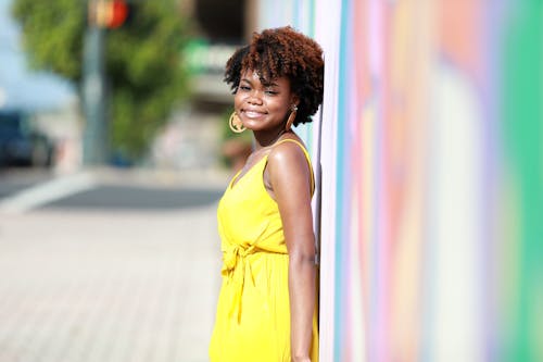 Beautiful Woman in Yellow Dress Posing by Wall