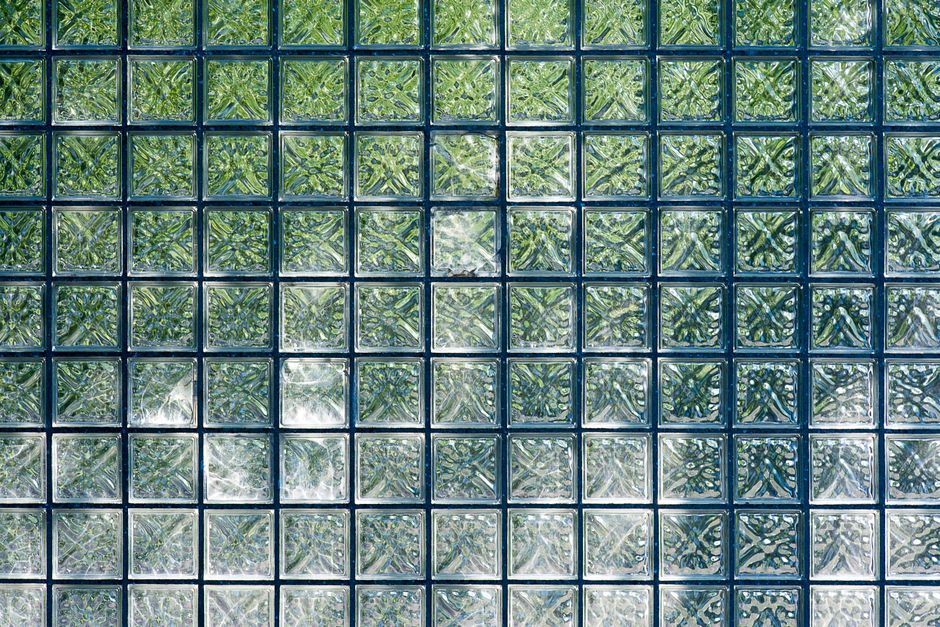 Close-up of square glass blocks creating a textured, geometric pattern in green hues.