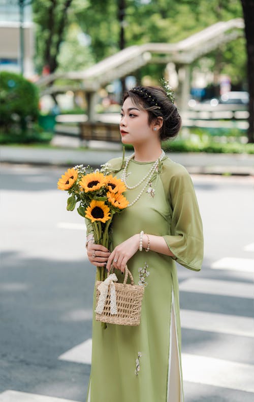 Model in a Vietnamese Ao Dai Dress Holding a Bouquet of Sunflowers and a Handbag