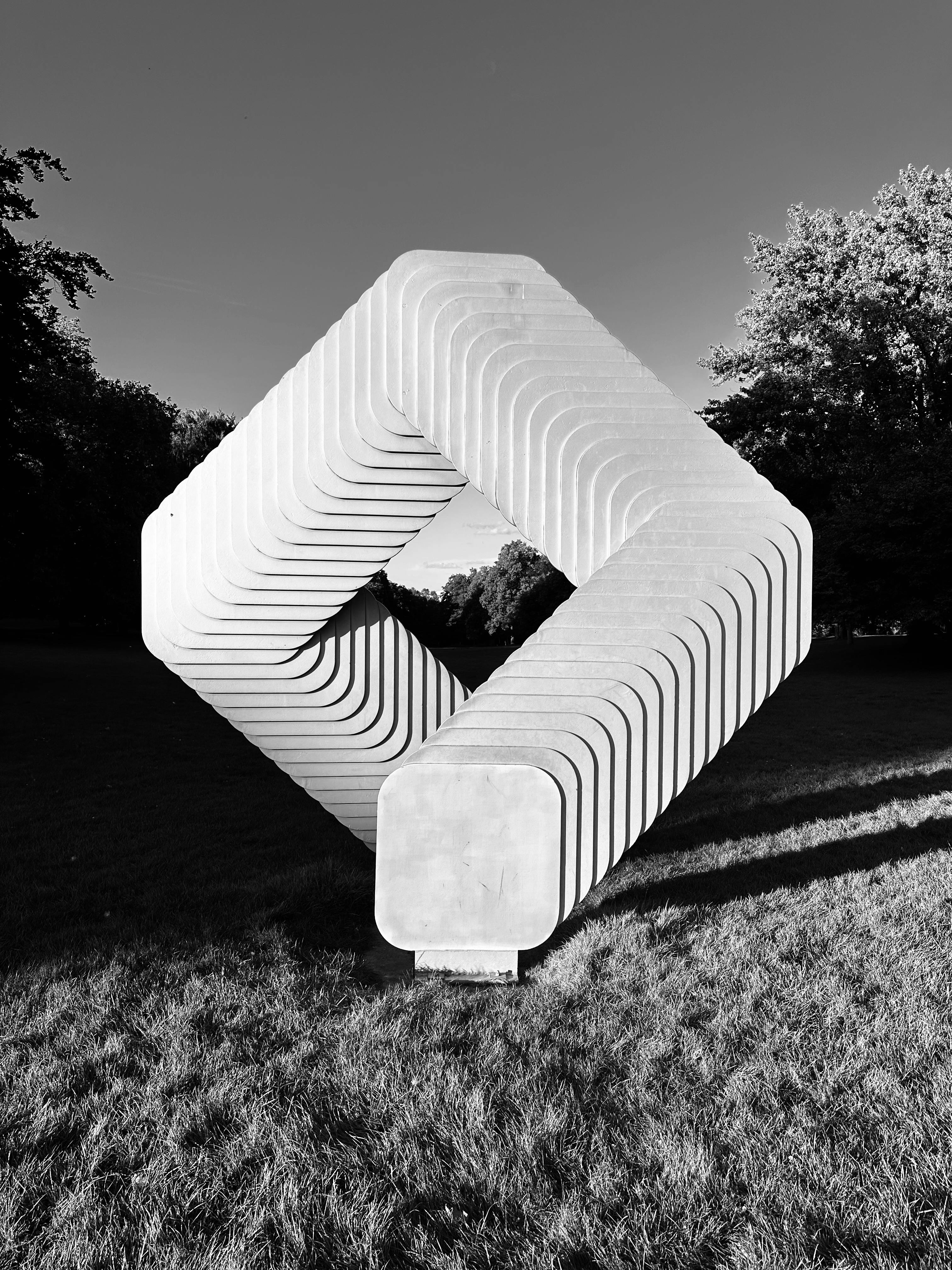 Monochrome geometric sculpture in a sunny park setting in Essen, Germany.