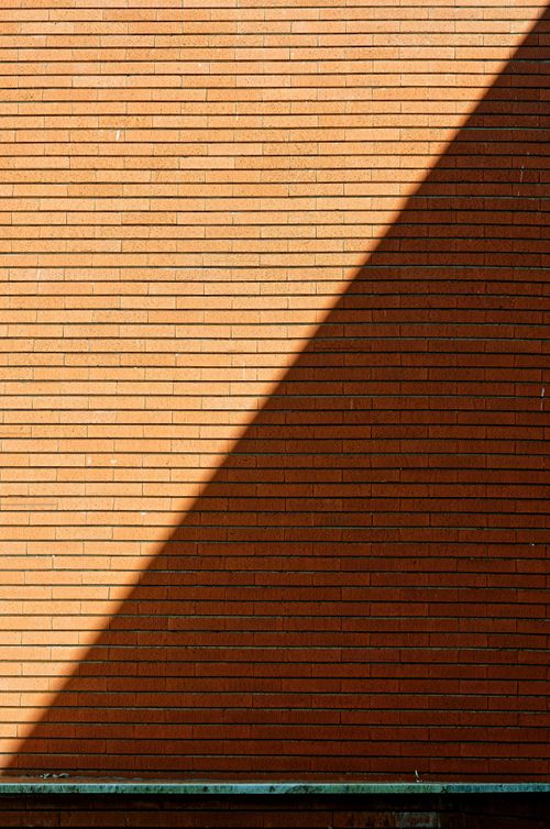Free A sunlit brick wall in Castiglione del Lago creates striking diagonal shadows. Stock Photo