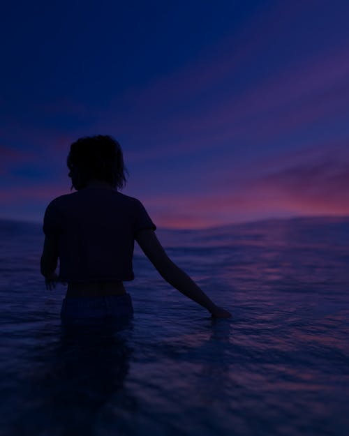 Person in Water Standing in Front of Purple Sky
