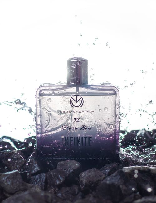 Free Luxury perfume bottle splashing in water against rocks, creating a premium feel. Stock Photo