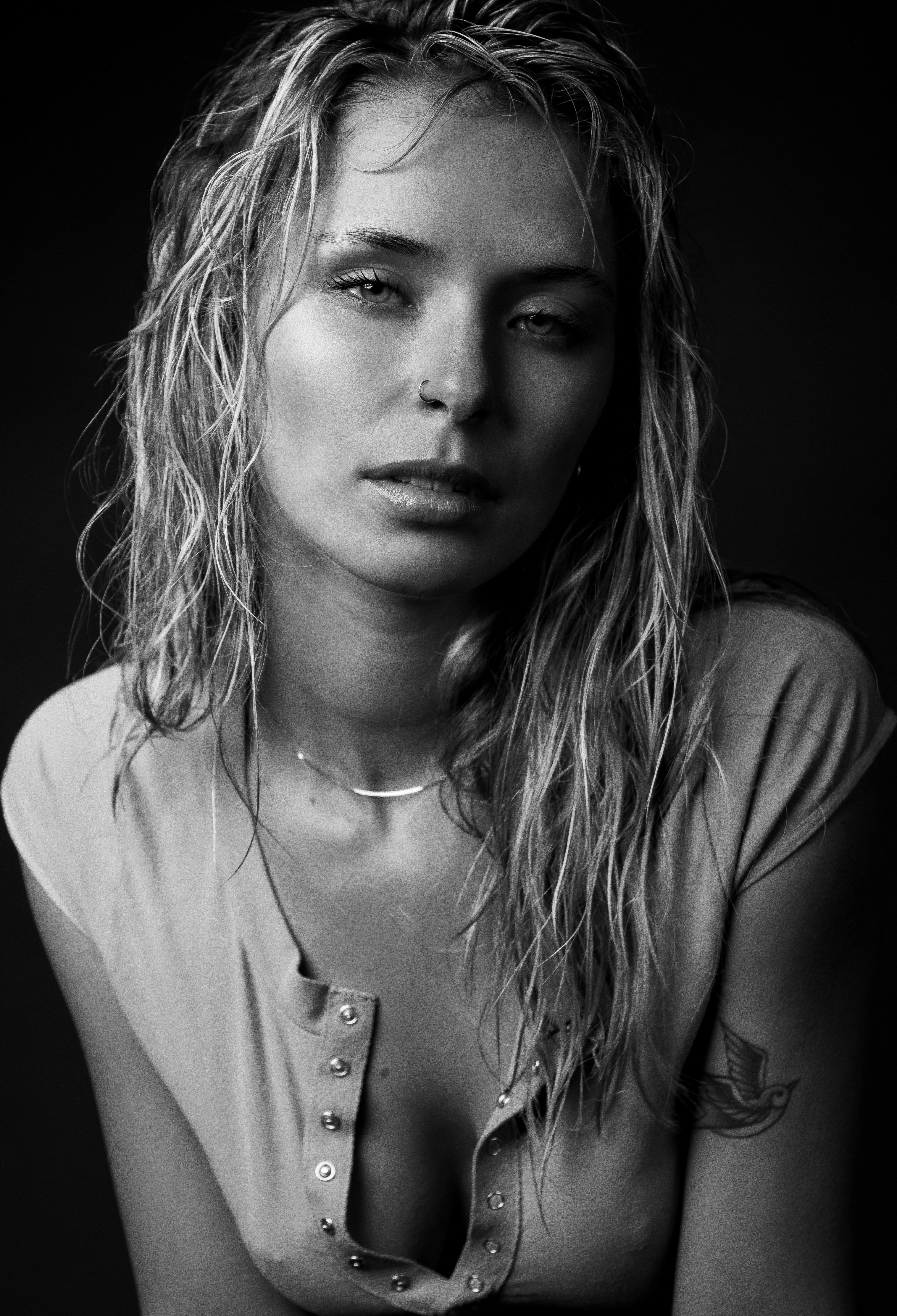 Striking black and white portrait of a woman with wet hair, capturing a moody essence.