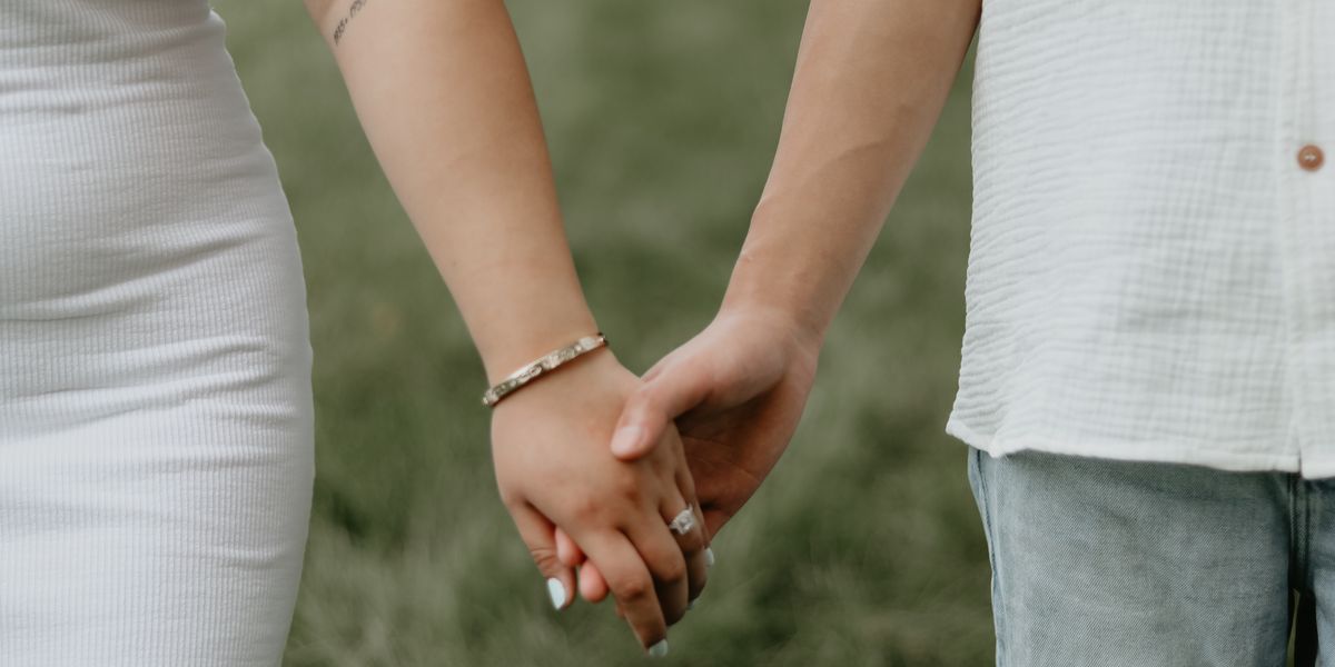 A couple holding hands as they walk outdoors together