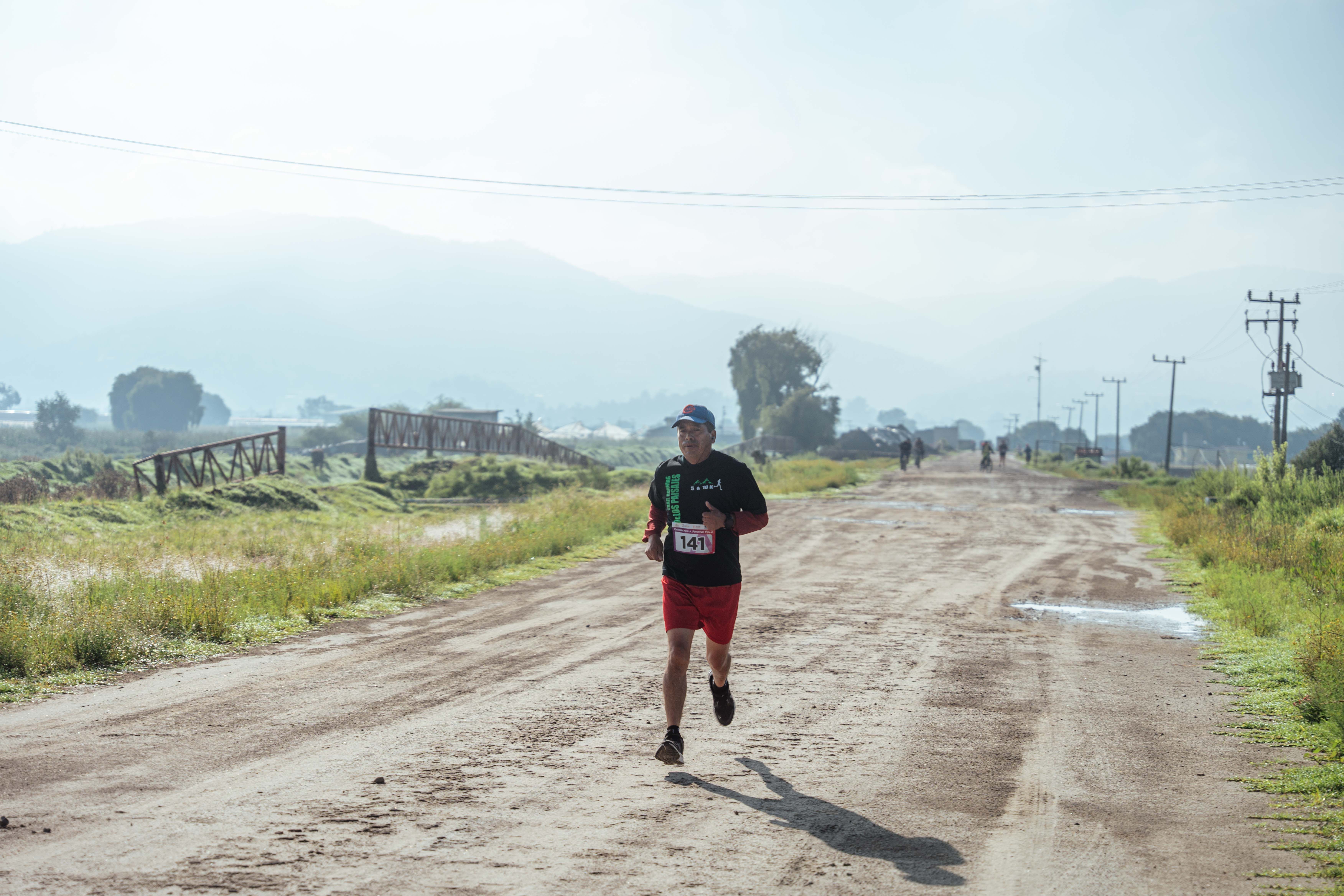 Man Running in Race on Dirt Road · Free Stock Photo