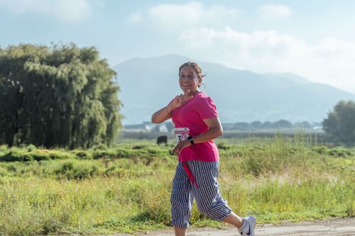 Free Happy woman gesturing peace sign while jogging in a countryside marathon. Stock Photo
