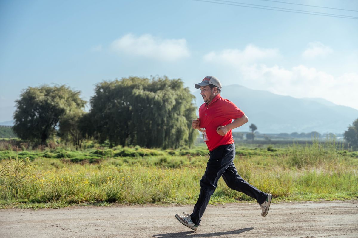 Adult male runner on a rural dirt road surrounded by hills and open countryside
