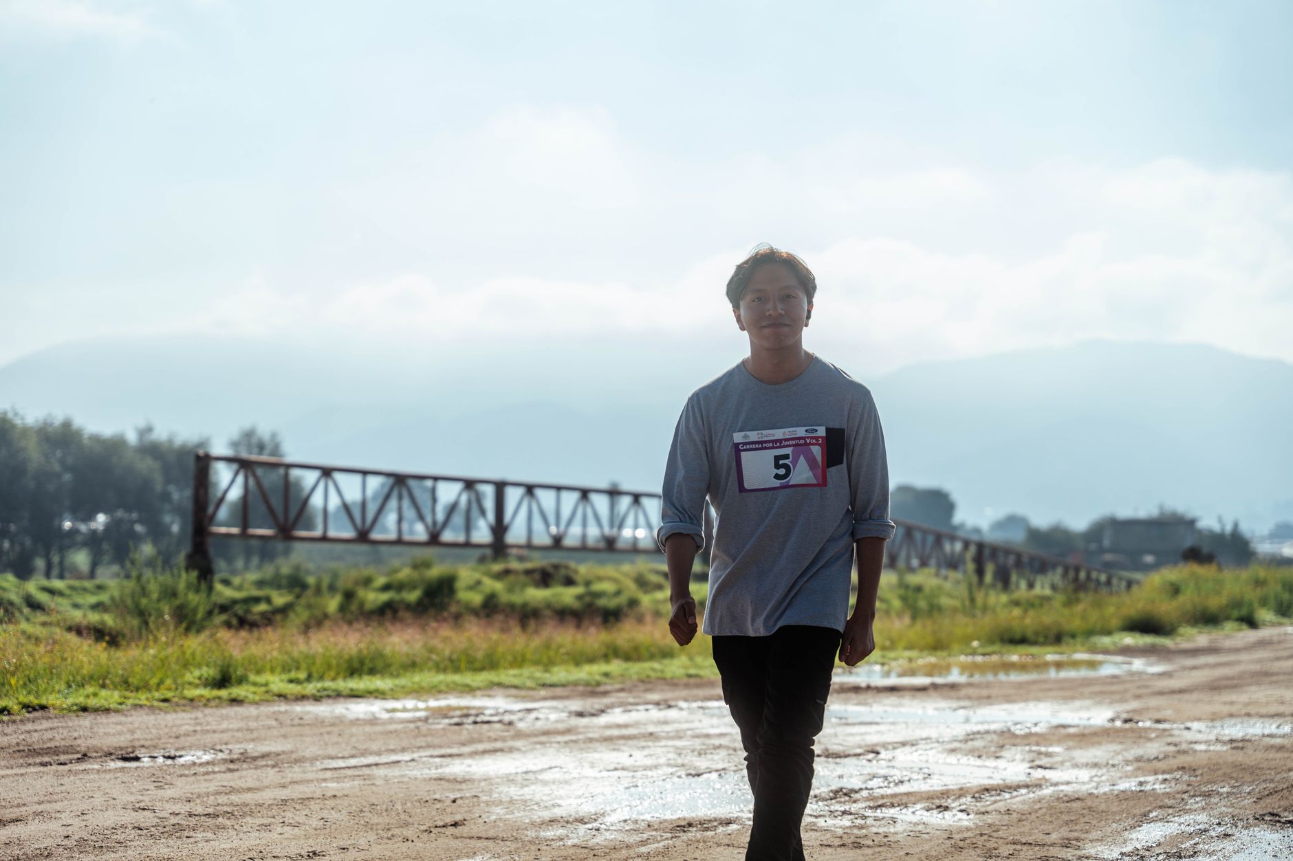 A runner walks on a sunny rural dirt road, showing sportsmanship and determination.