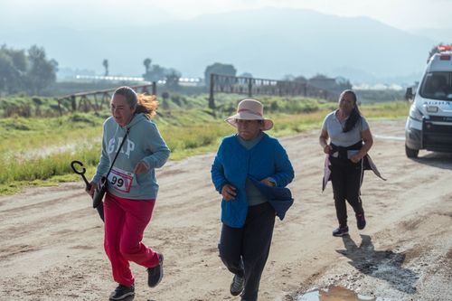 Free Three women participating in a rural outdoor run, with an ambulance in the backdrop. Stock Photo