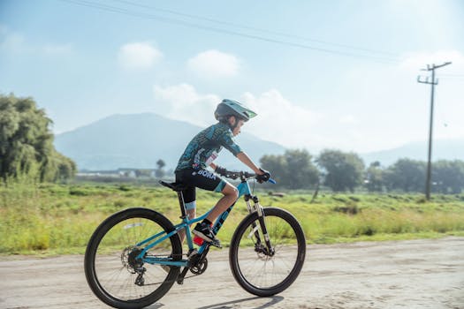 A boy wearing a helmet rides a bicycle on a scenic rural dirt road during summer.