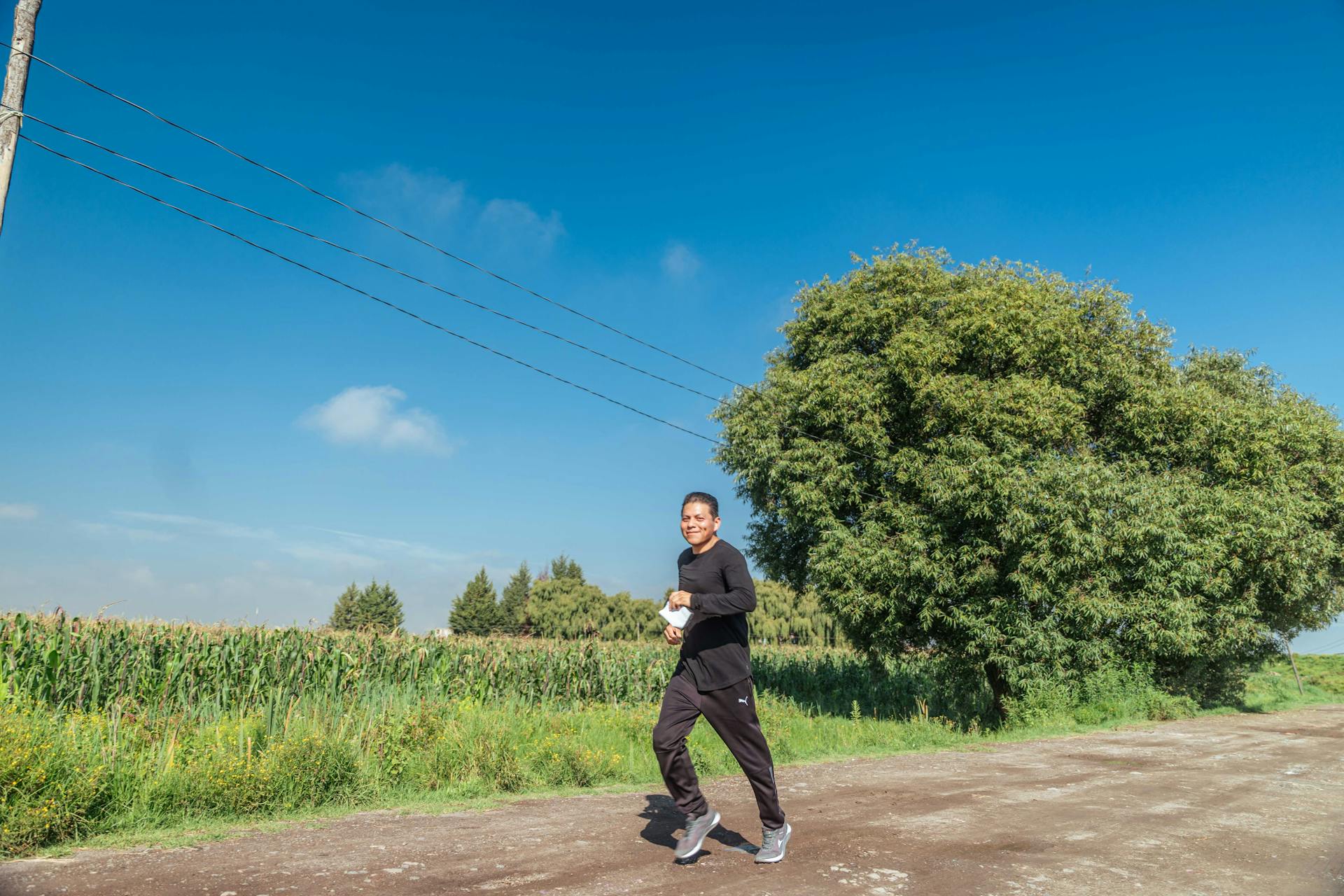 Man Running on Dirt Road near Field