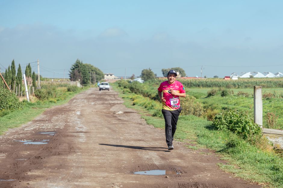 A man jogs on a rural dirt road, enjoying a sunny day in the countryside.
