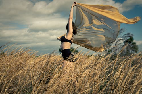 Woman Holding Up a See-through Shawl on a Field 