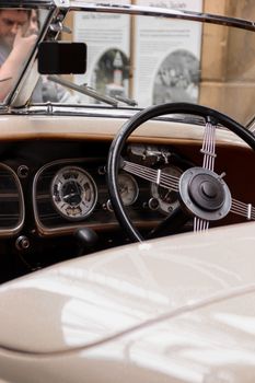 Close-up of a vintage car interior featuring a classic dashboard and steering wheel in a convertible car.