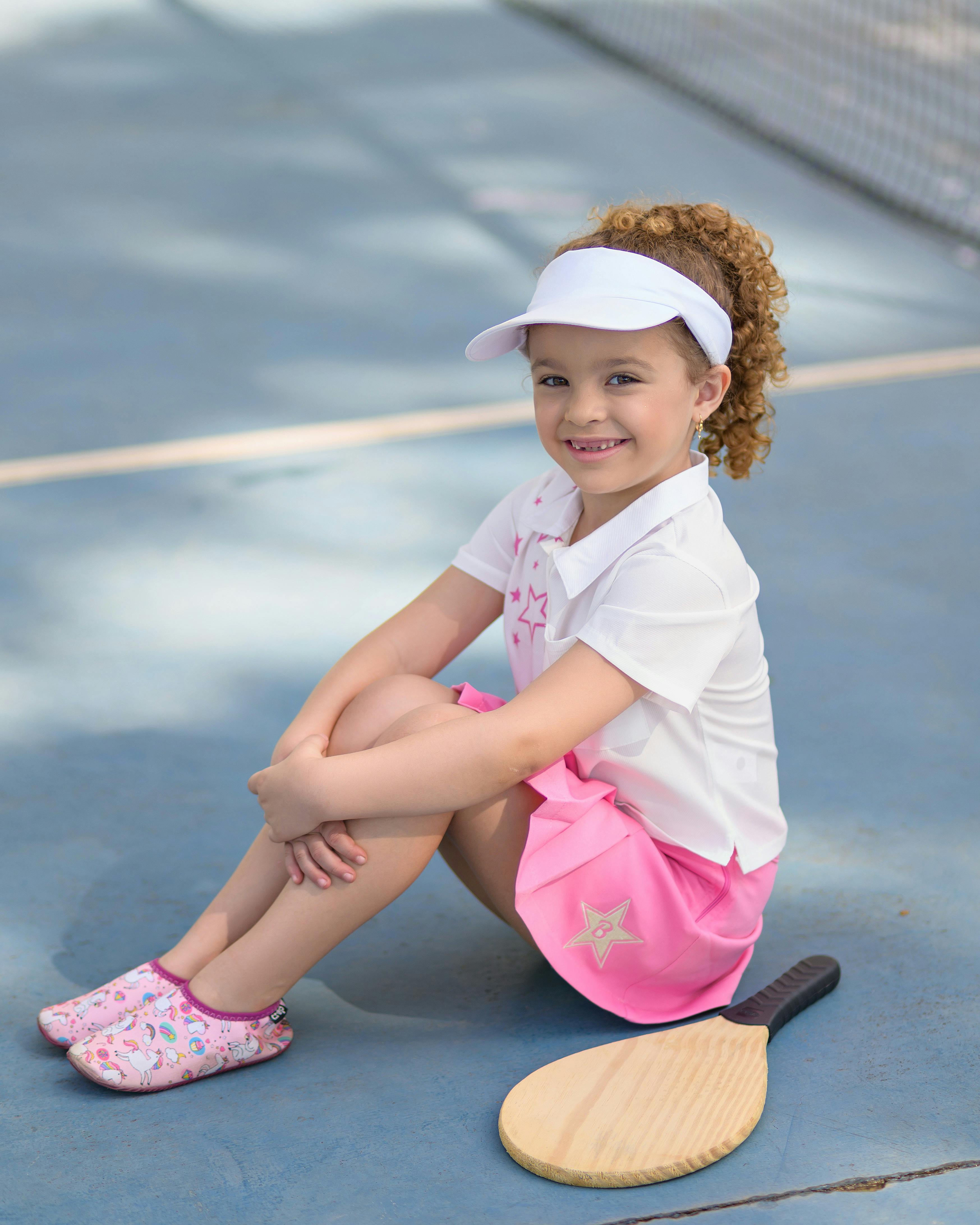 smiling girl with tennis racket sitting on court