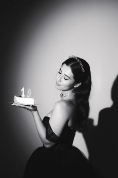 Young woman celebrating her 19th birthday with a cake in an elegant black dress.