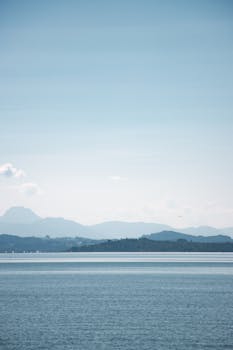 Calm waters of Chiemsee Lake with the Bavarian Alps in the background under a clear sky.