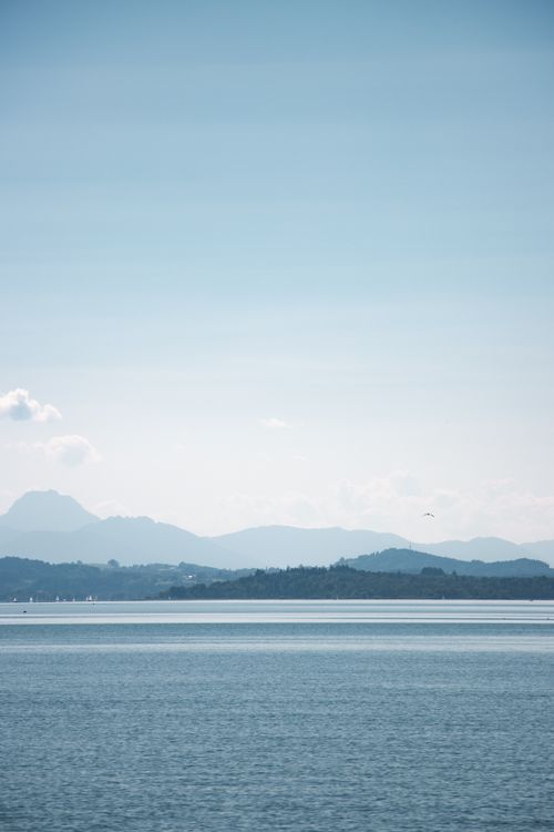 Free Calm waters of Chiemsee Lake with the Bavarian Alps in the background under a clear sky. Stock Photo
