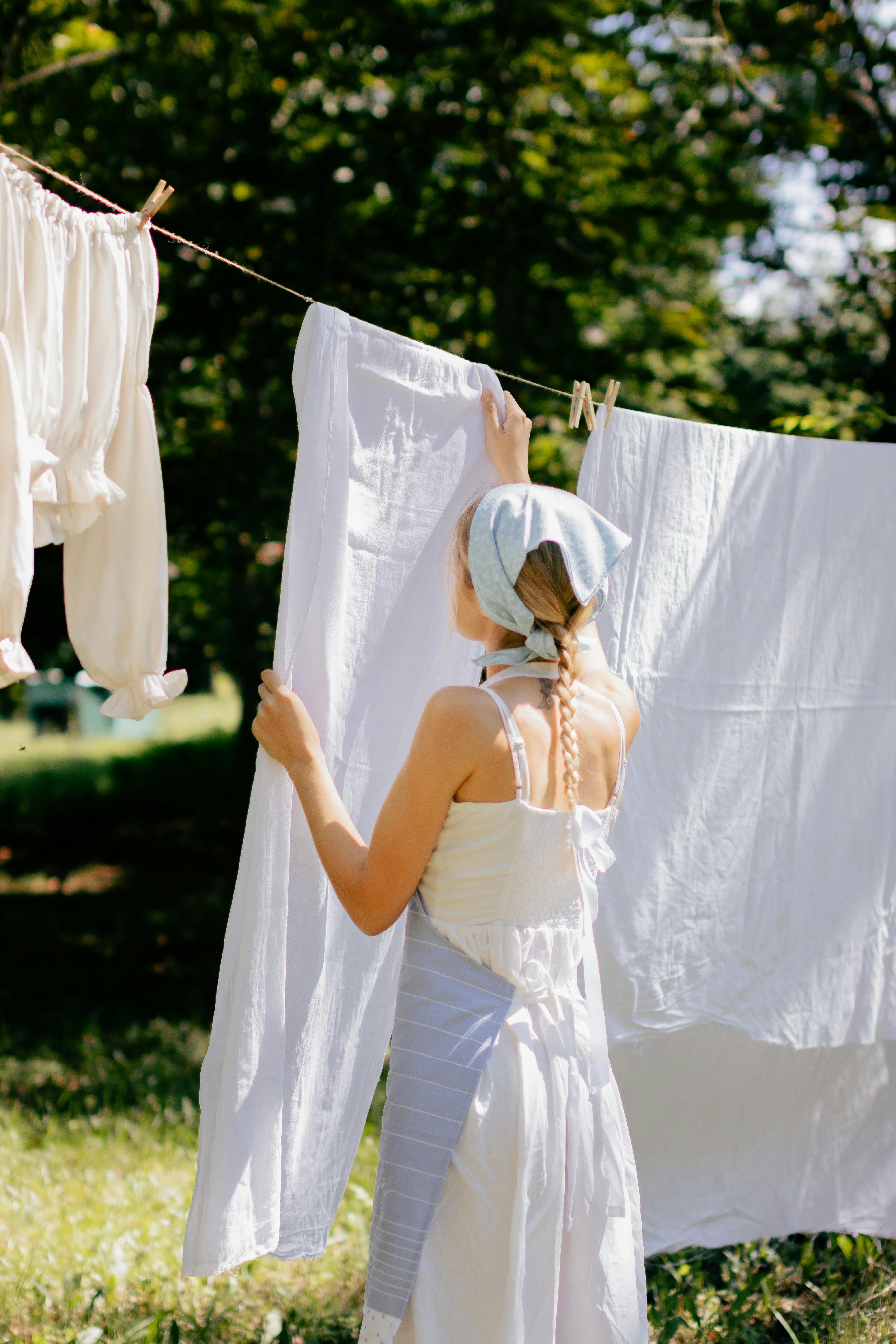 Young Woman in Handkerchief and Apron Hanging Laundry in Garden · Free ...