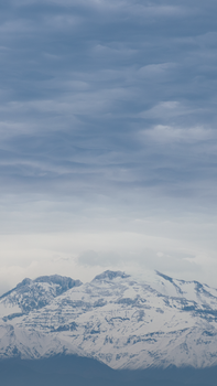 Serene snow-covered mountain peaks under a cloudy winter sky.