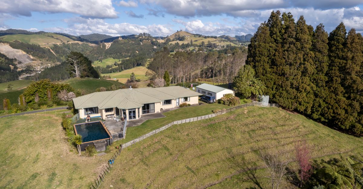 Aerial view of a luxurious mansion surrounded by lush hills in Tauranga, New Zealand.