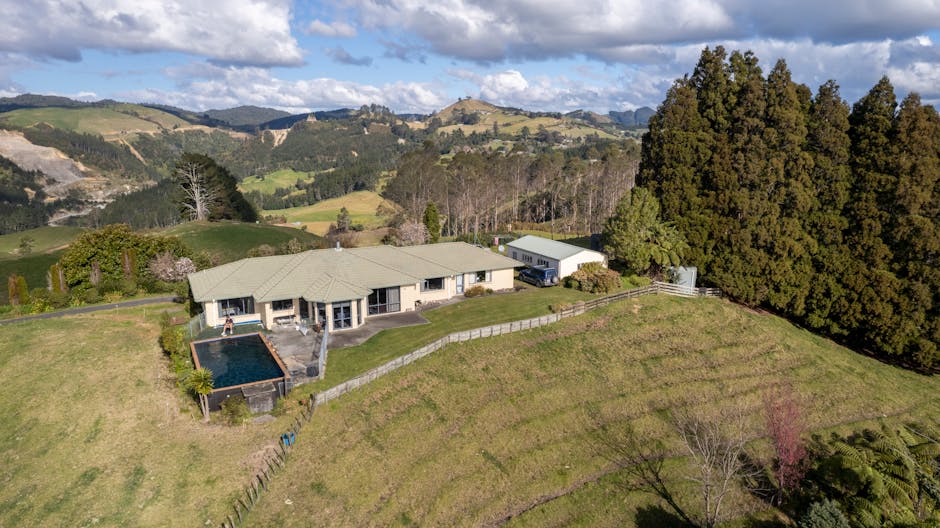 Aerial view of a luxurious mansion surrounded by lush hills in Tauranga, New Zealand.