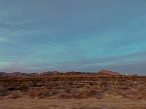 Free Expansive arid desert with scrub vegetation beneath a clear blue sky, perfect for nature and travel imagery. Stock Photo