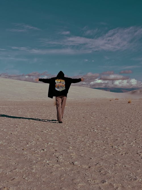 Person in Hoodie Walking on Barren Desert