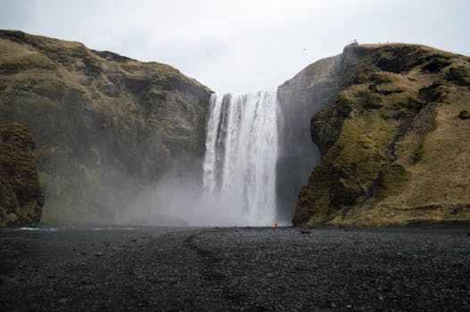 Explore the stunning Skógafoss waterfall in Iceland, surrounded by moss-covered cliffs and black sand.