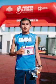 Young athlete proudly stands after completing a race, showing a thumbs-up gesture.