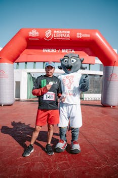 Runner poses with a mascot at the race finish line, portraying joy and achievement.
