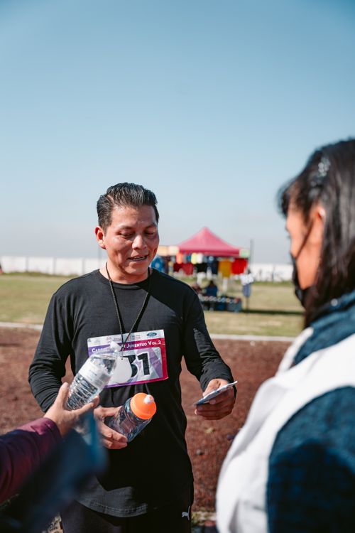 Free A male runner in sportswear receives water and support after completing a track event outdoors. Stock Photo