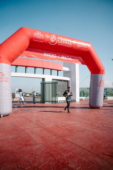 Athlete crossing the finish line at a marathon event under a branded arch in Lerma, Mexico.